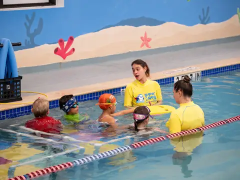 Smiling baby in the water with a Super Aqua instructor